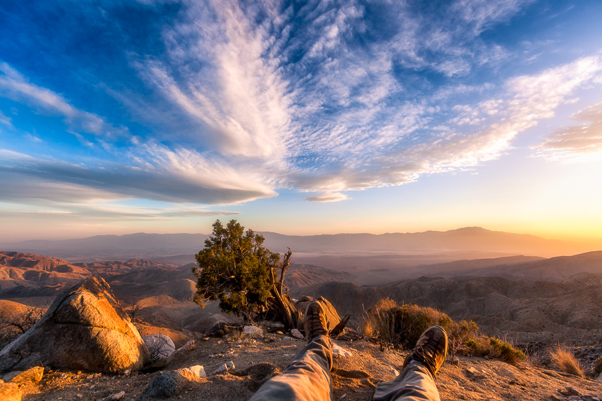a photograph of feet on the edge of a view point in joshua tree national park during sunset